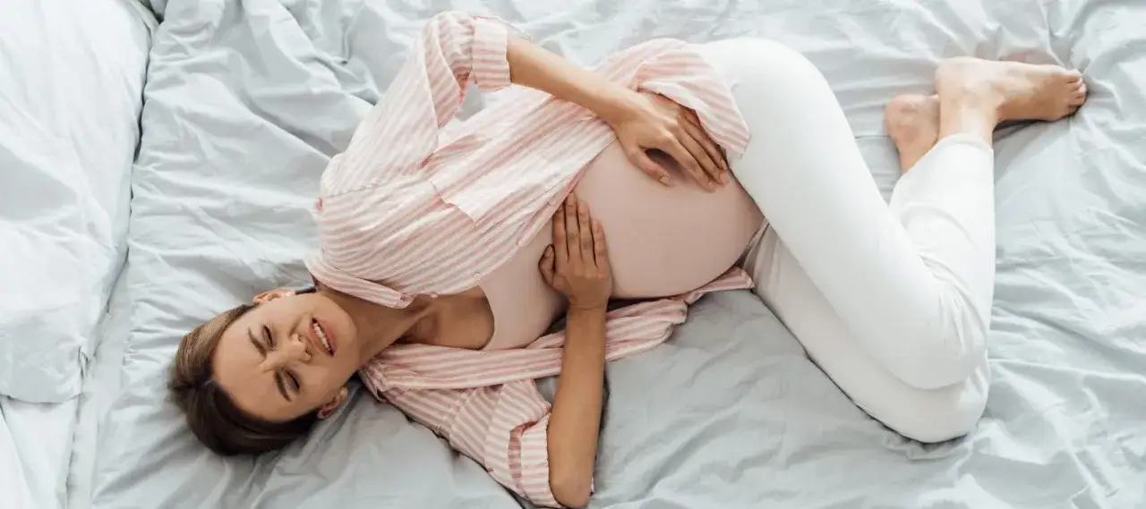 Kobieta w ciąży z bólem brzucha i dzwoniąca po pomoc