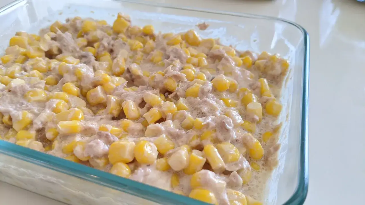 Ein cremiger Thunfischsalat mit Mais in einer Glasform, bereit zum Servieren.