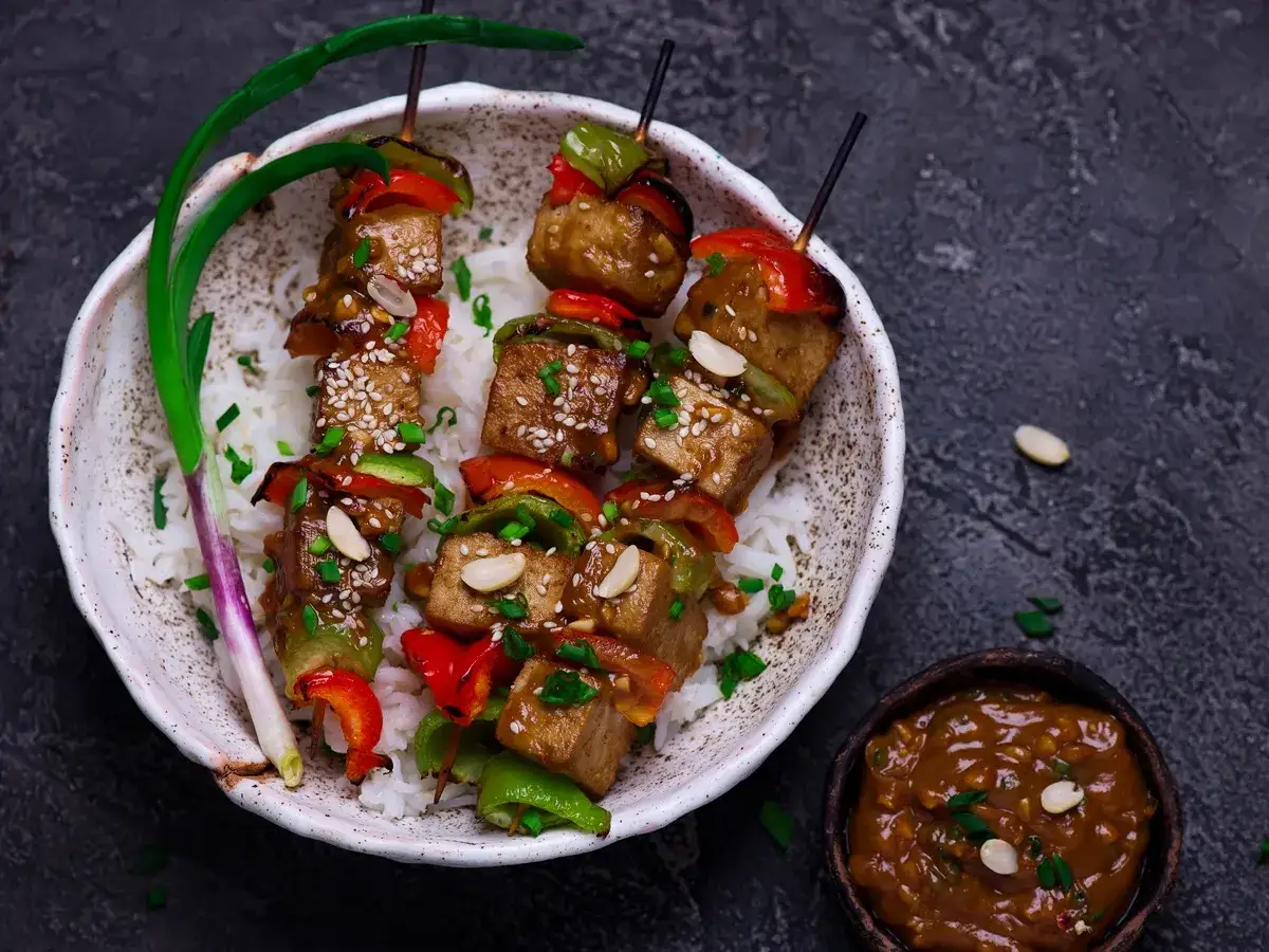 Pyszne szaszłyki z tofu i warzywami na ryżu, idealne wege grill przepisy. Posypane sezamem i orzeszkami ziemnymi.