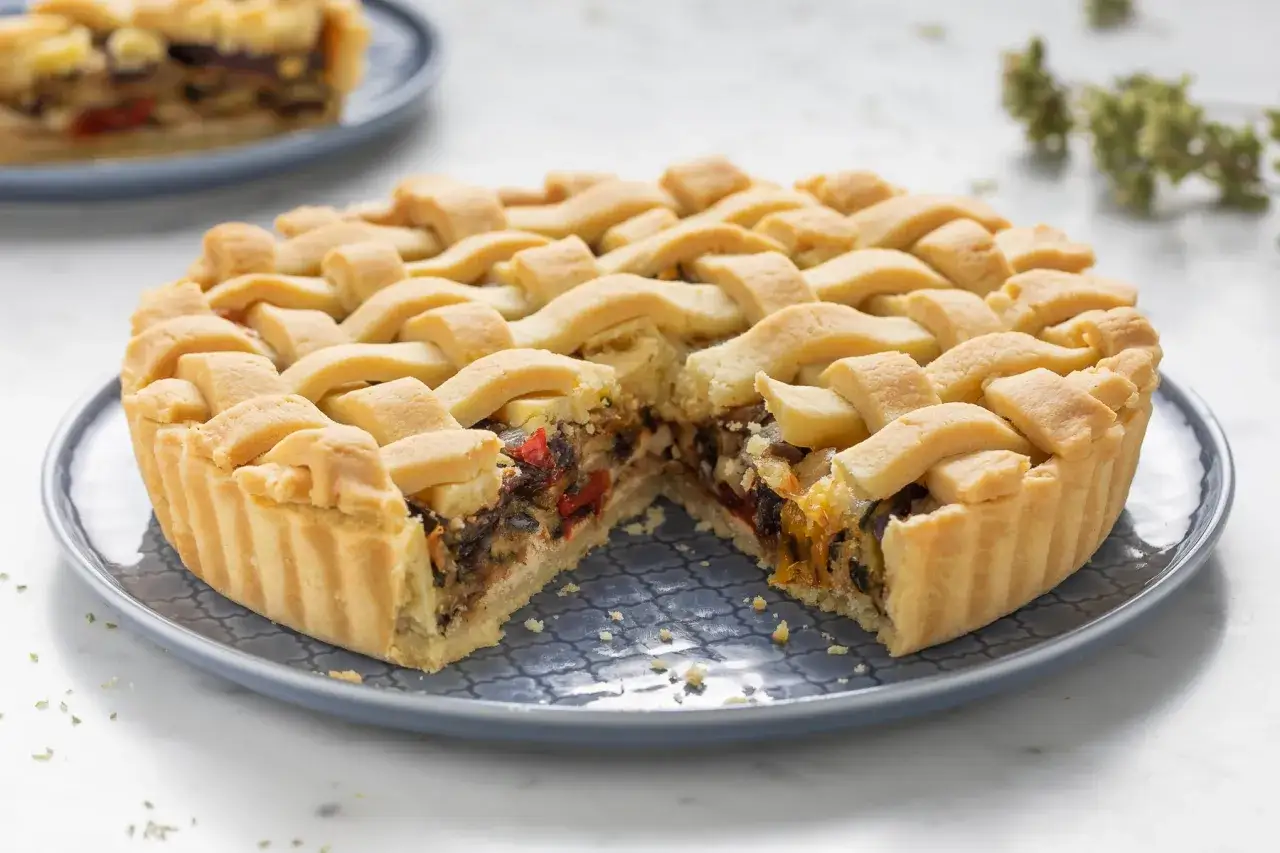 Crostata morbida salata con verdure miste e formaggio, con una griglia di pasta dorata.