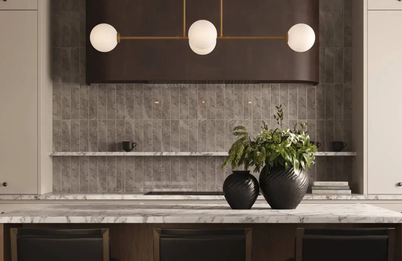Moderne K&uuml;che mit grauen Wandfliesen, die leicht zu reinigen sind. Marmor-Arbeitsplatte, schwarze Vasen mit Pflanzen und eine H&auml;ngeleuchte.