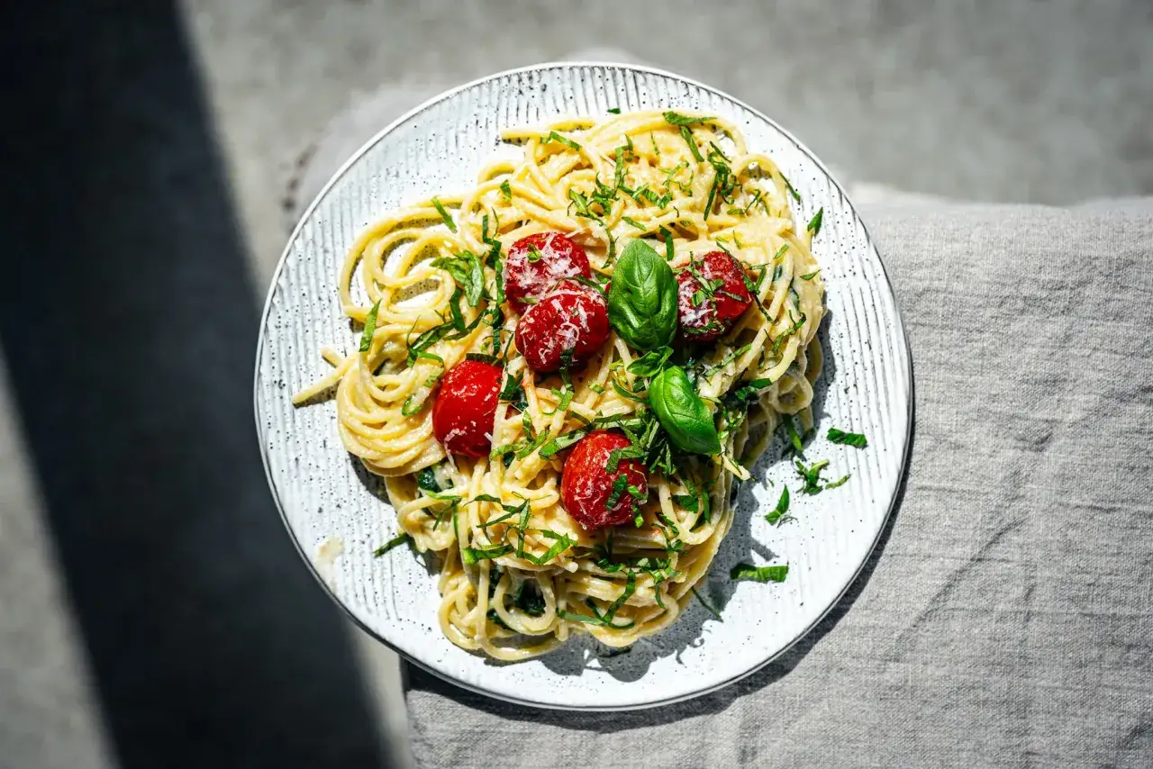 Spaghetti mit cremigem Pesto Trapanese, Kirschtomaten und Basilikum, garniert mit Parmesan.