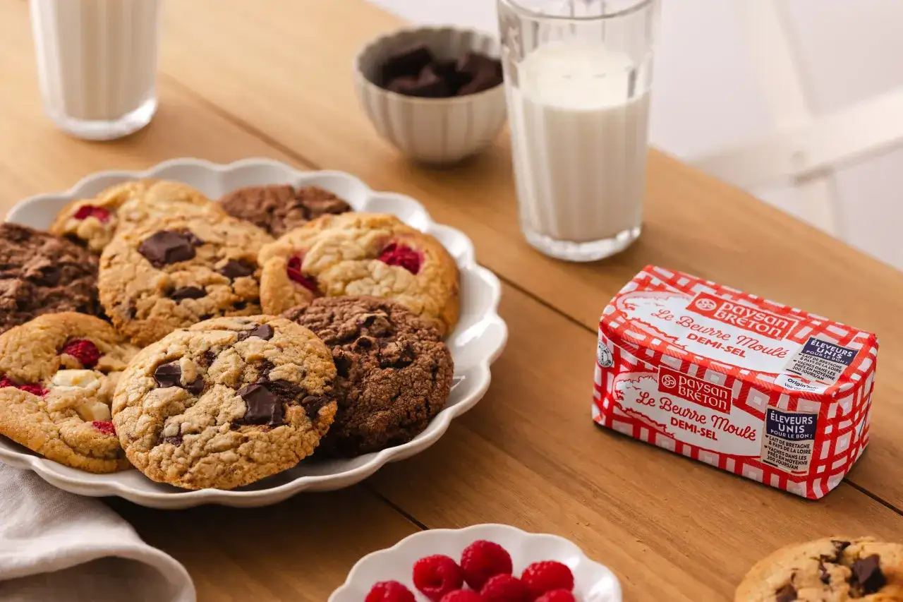 Assiette de cookies chocolat, framboise et blancs, avec un verre de lait et du beurre Breton.