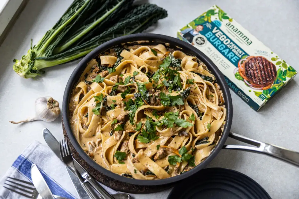 Kr&auml;mig vegetarisk carbonara med tagliatelle, gr&ouml;nk&aring;l och svamp. Bredvid syns en f&ouml;rpackning med vegoburgare.