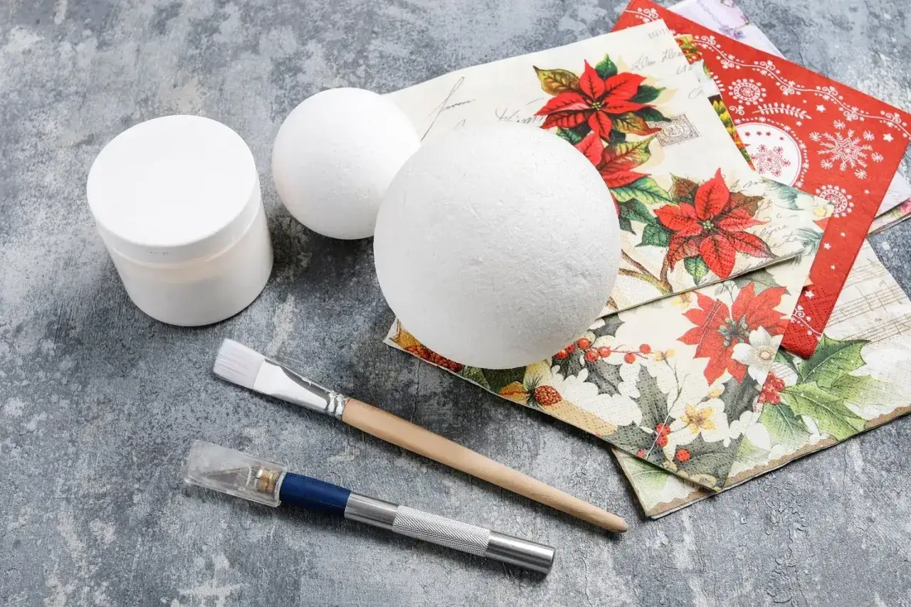 Materiały do decoupage krok po kroku: styropianowe kule, klej, pędzel i świąteczne serwetki.