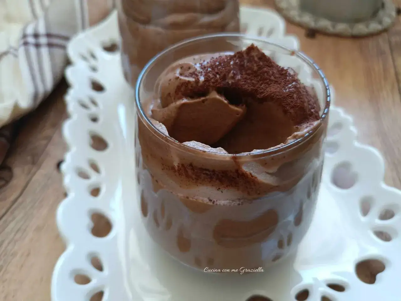 Deliziosa ricetta crema di caffè senza panna, spolverata di cacao, servita in bicchieri su un vassoio bianco traforato.