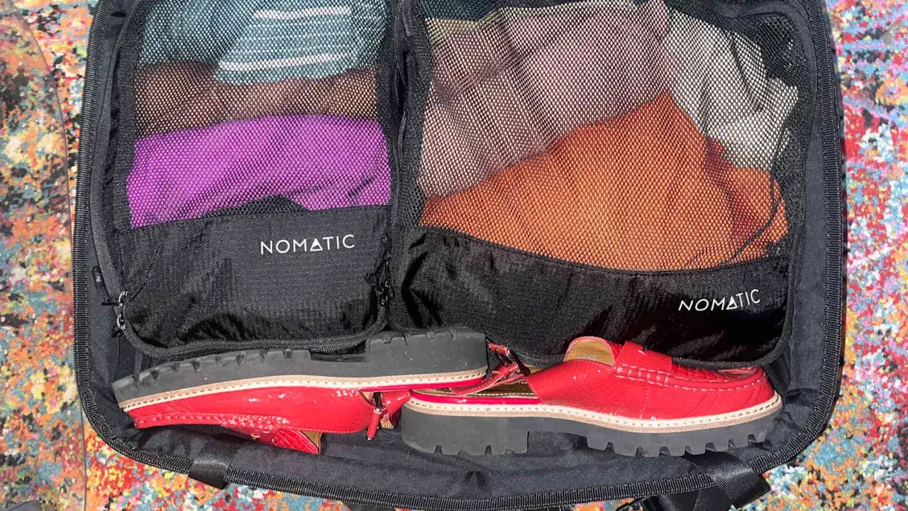 Astuce pour comment ranger des chaussures dans une valise : placez-les &agrave; plat au fond, entre les organisateurs de v&ecirc;tements.