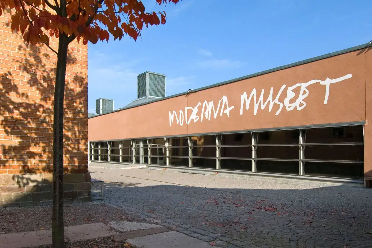Moderna Museet Stockholm med orange fasad och stora f&ouml;nster. H&ouml;stf&auml;rger p&aring; tr&auml;det.