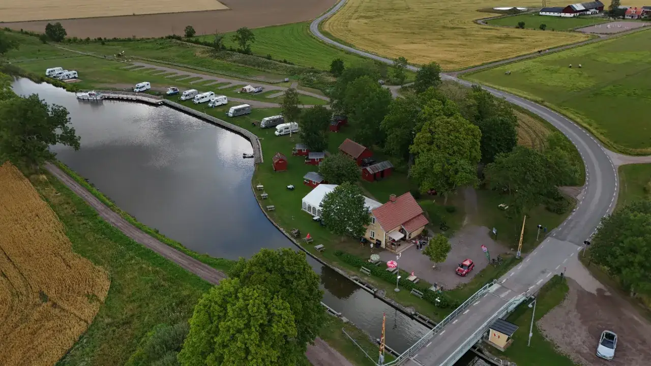 Jonsboda camping vid en kanal med husbilar, stugor och en gul byggnad.