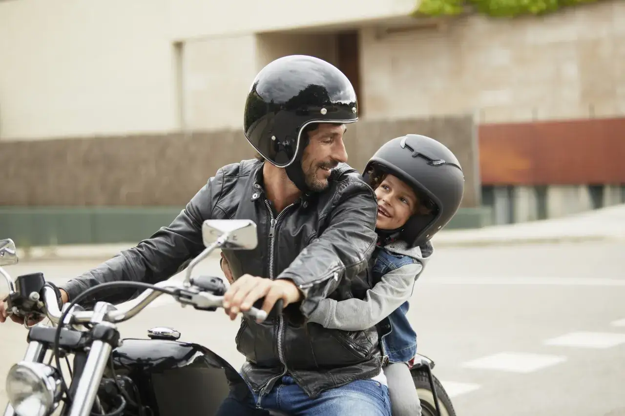 Rodzic z dzieckiem na motocyklu, bezpieczna jazda, kaski