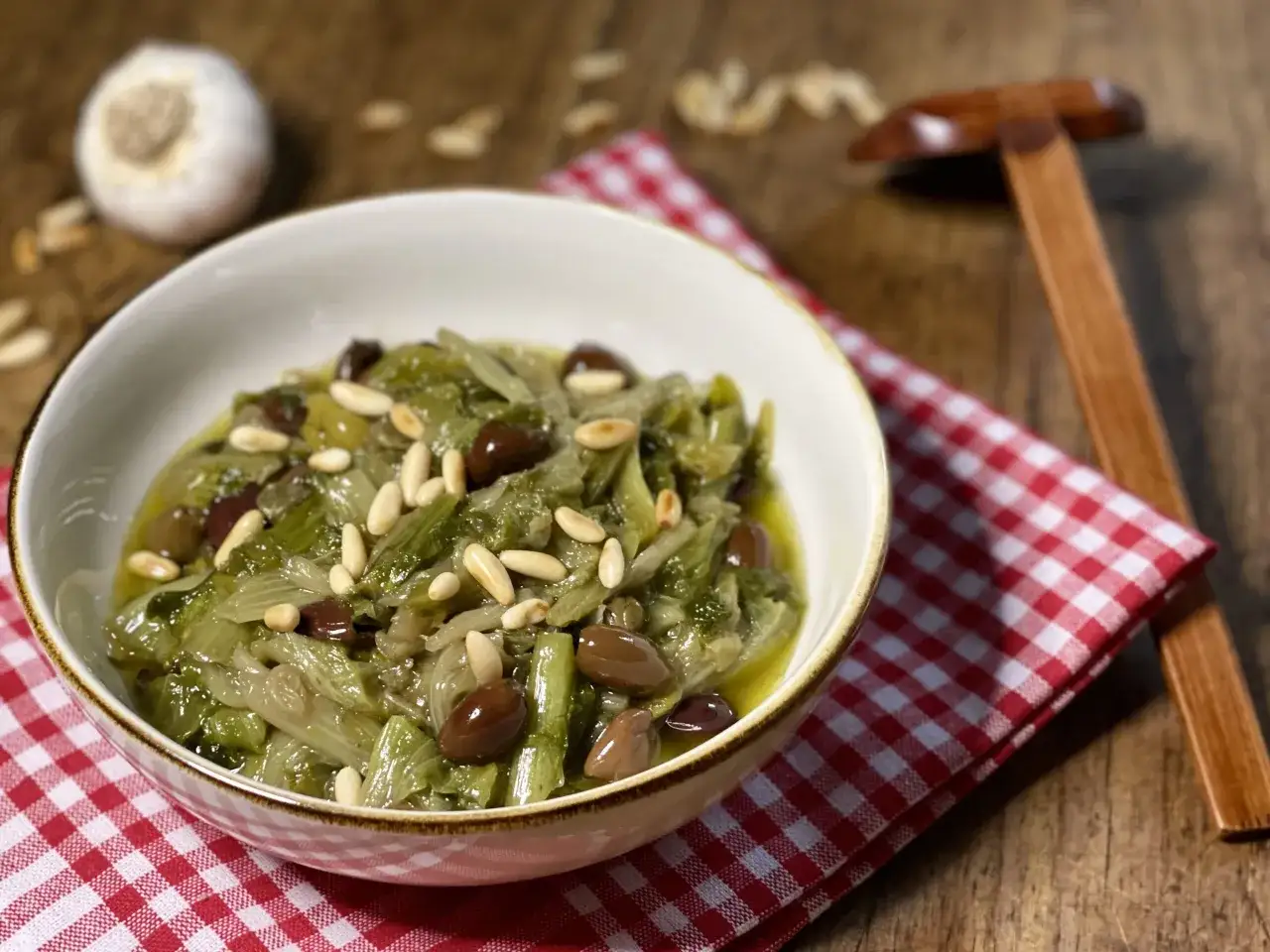 Scarola in padella con olive e pinoli, un piatto semplice e gustoso, pronto per essere servito.