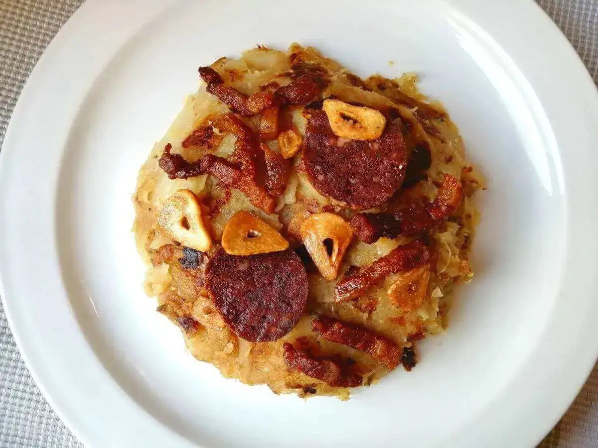 Delicioso trinxat de la Cerdanya, un plato tradicional con patata, col, tocino crujiente, chorizo y ajo frito.