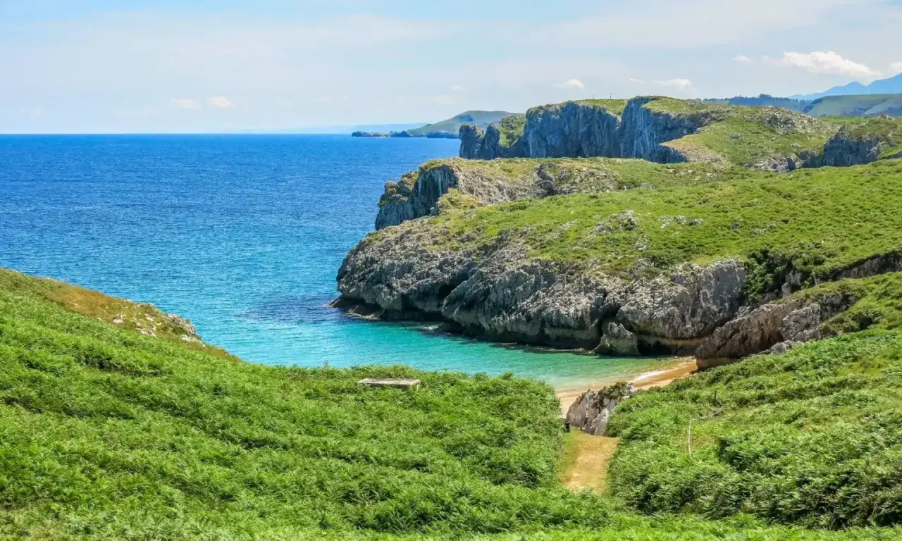 Malownicze wybrzeże Camino del Norte. Turkusowa woda, skaliste klify i bujna zieleń tworzą zapierający dech w piersiach krajobraz.