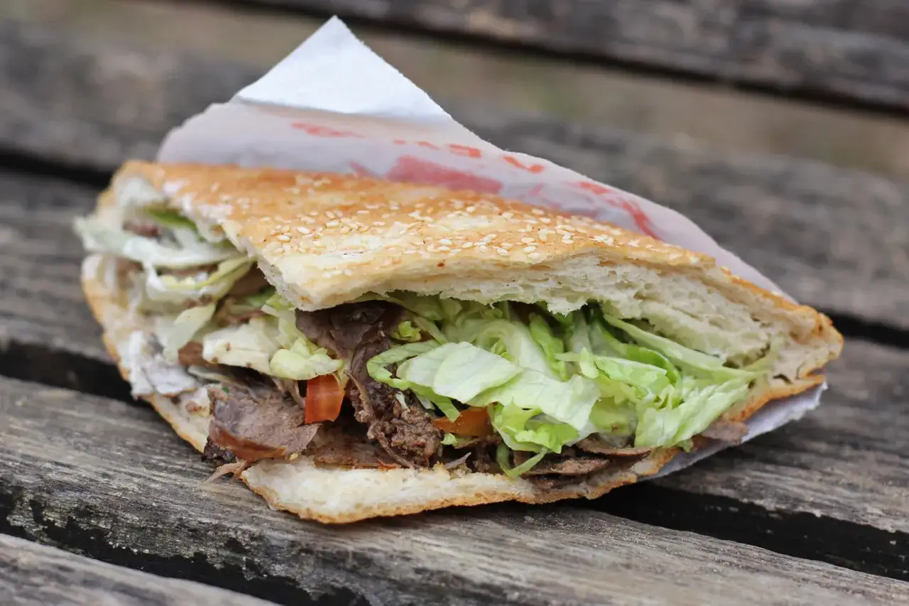 Pyszny kebab w bułce z sezamem, pełen mięsa i świeżej sałaty. Pytanie, skąd pochodzi kebab, jest równie intrygujące, co jego smak.