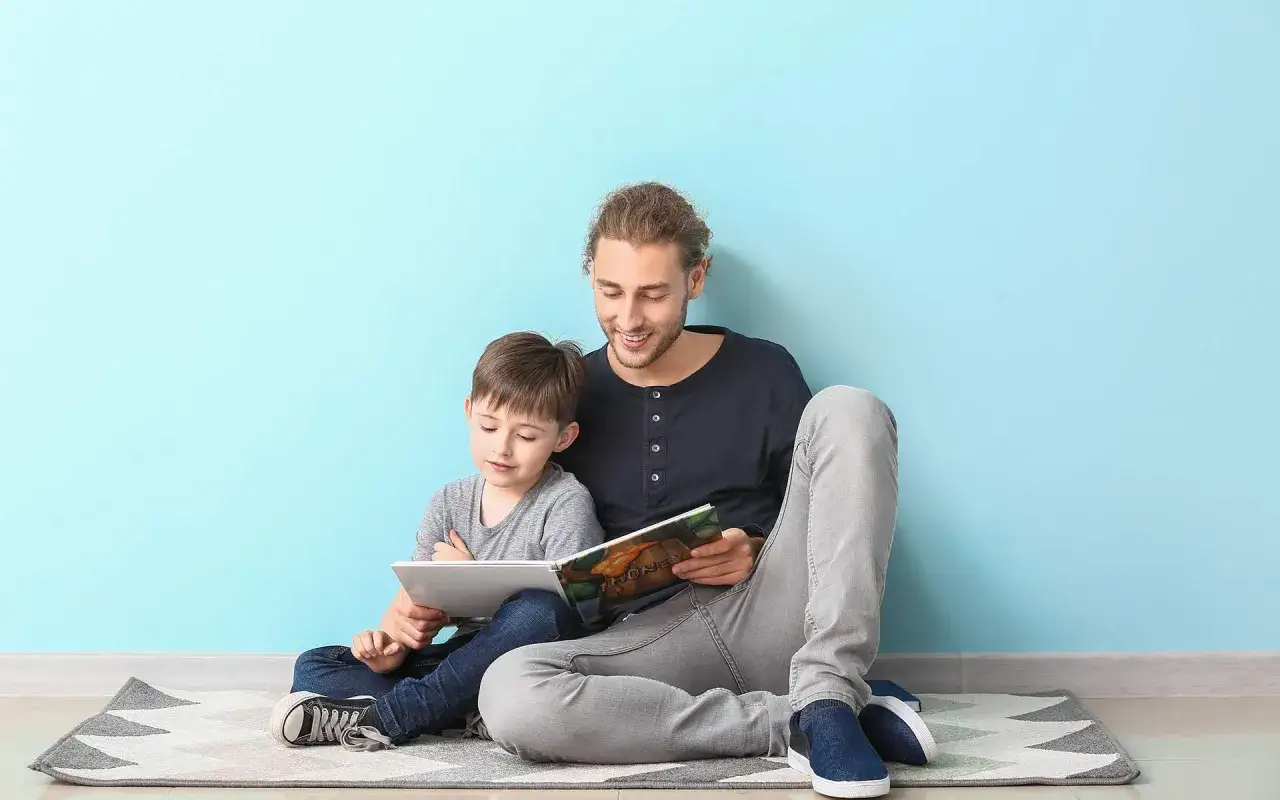 Ein Mann liest einem Kind ein Buch vor. Der Junge hört aufmerksam zu, während der Mann ihm eine Geschichte erzählt, vielleicht einen meditationstext zum vorlesen.
