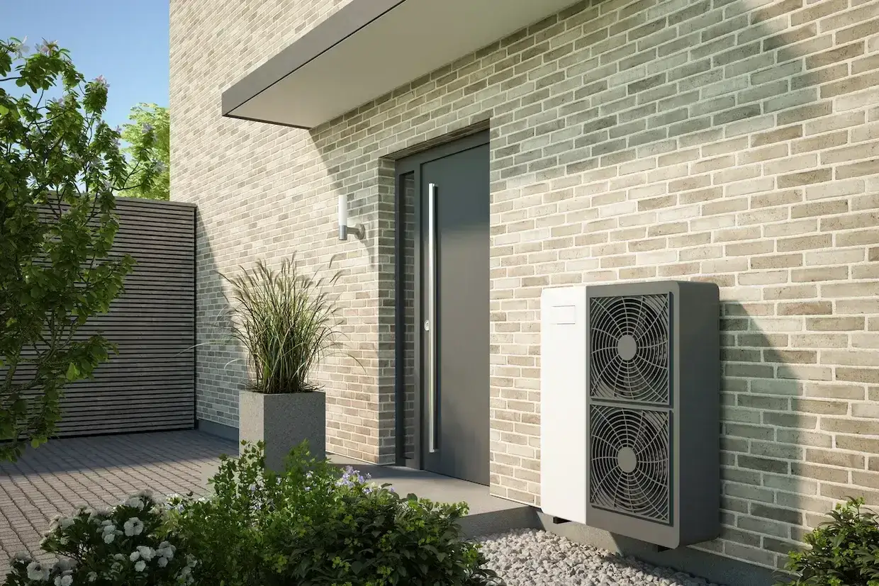 Unit&eacute; ext&eacute;rieure de chauffage et climatisation avis, discr&egrave;te et moderne, install&eacute;e pr&egrave;s de l'entr&eacute;e d'une maison en briques claires.