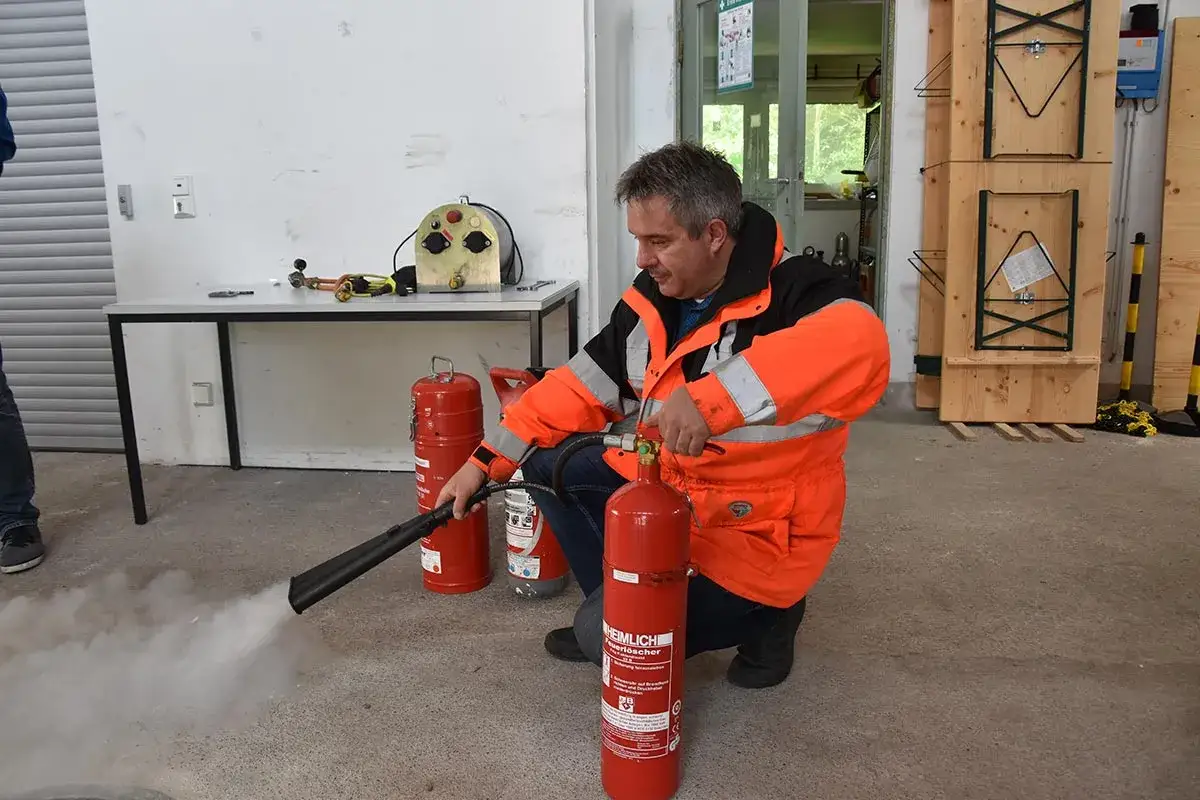 Mann in Warnweste &uuml;bt mit Feuerl&ouml;scher. Auffrischung Sicherheitsbeauftragter im Einsatz.
