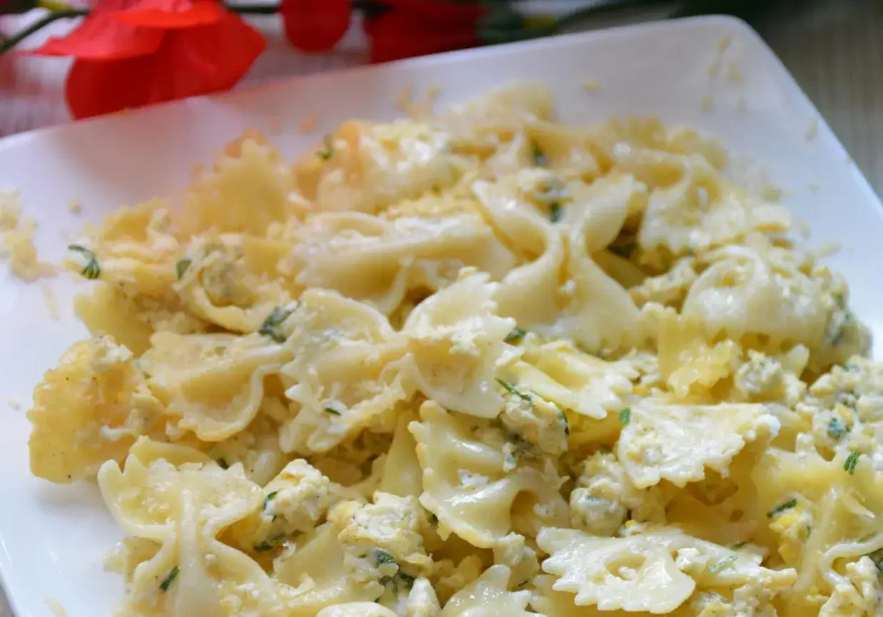 Pyszny makaron farfalle z jajkiem i ziołami, posypany startym serem. Idealny na szybki obiad.