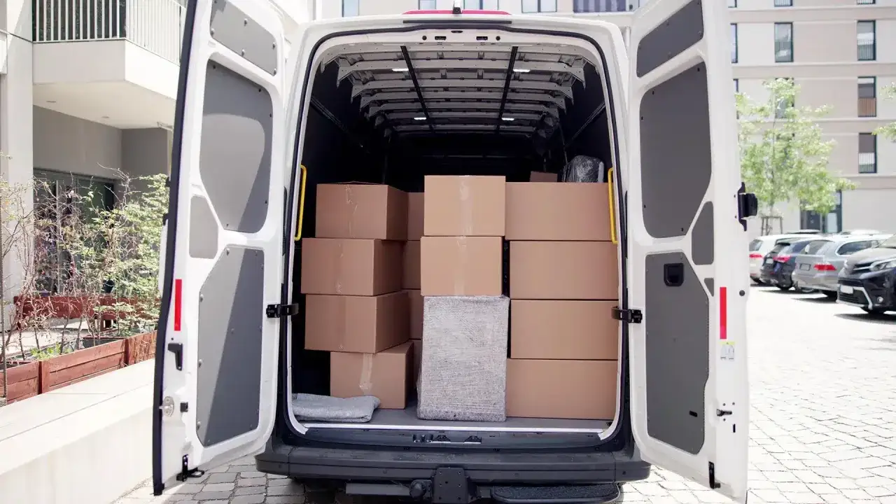 Ein wei&szlig;er Transporter ist voll beladen mit braunen Paketen. Was ist ein Transporter? Ein Fahrzeug f&uuml;r Lieferungen und Transporte.