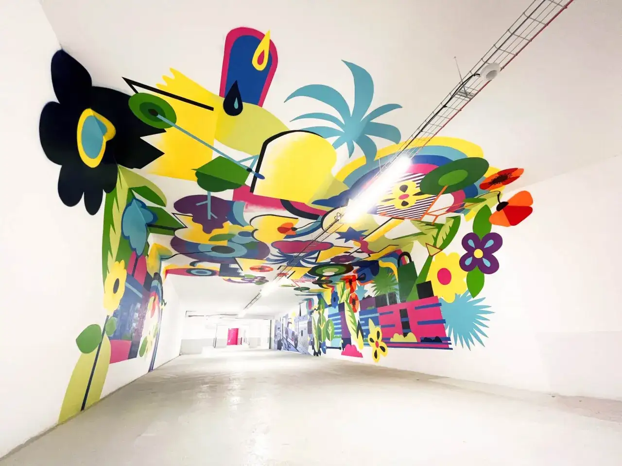 Une fresque dessin colorée et abstraite orne les murs et le plafond d'un couloir, évoquant un paysage végétal stylisé.