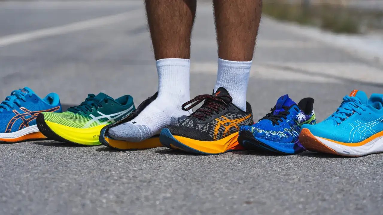 Asics co to za firma? Pięć par kolorowych but&oacute;w do biegania marki Asics ustawionych na asfalcie.