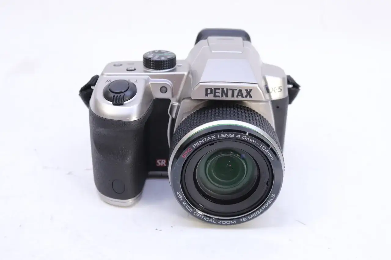 Silver Pentax X5 kamera med svart grepp och en stor lins. Perfekt f&ouml;r att f&aring;nga dina &auml;ventyr.