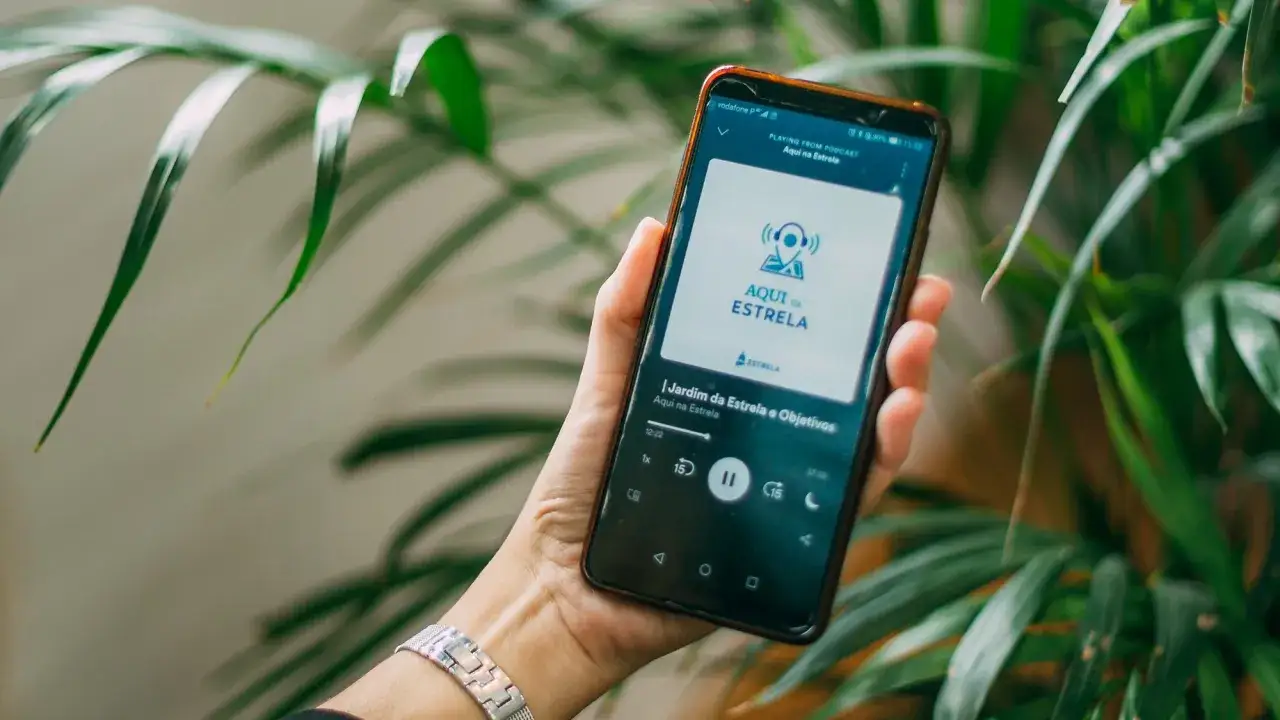 Main d'une personne tenant un smartphone affichant le podcast 