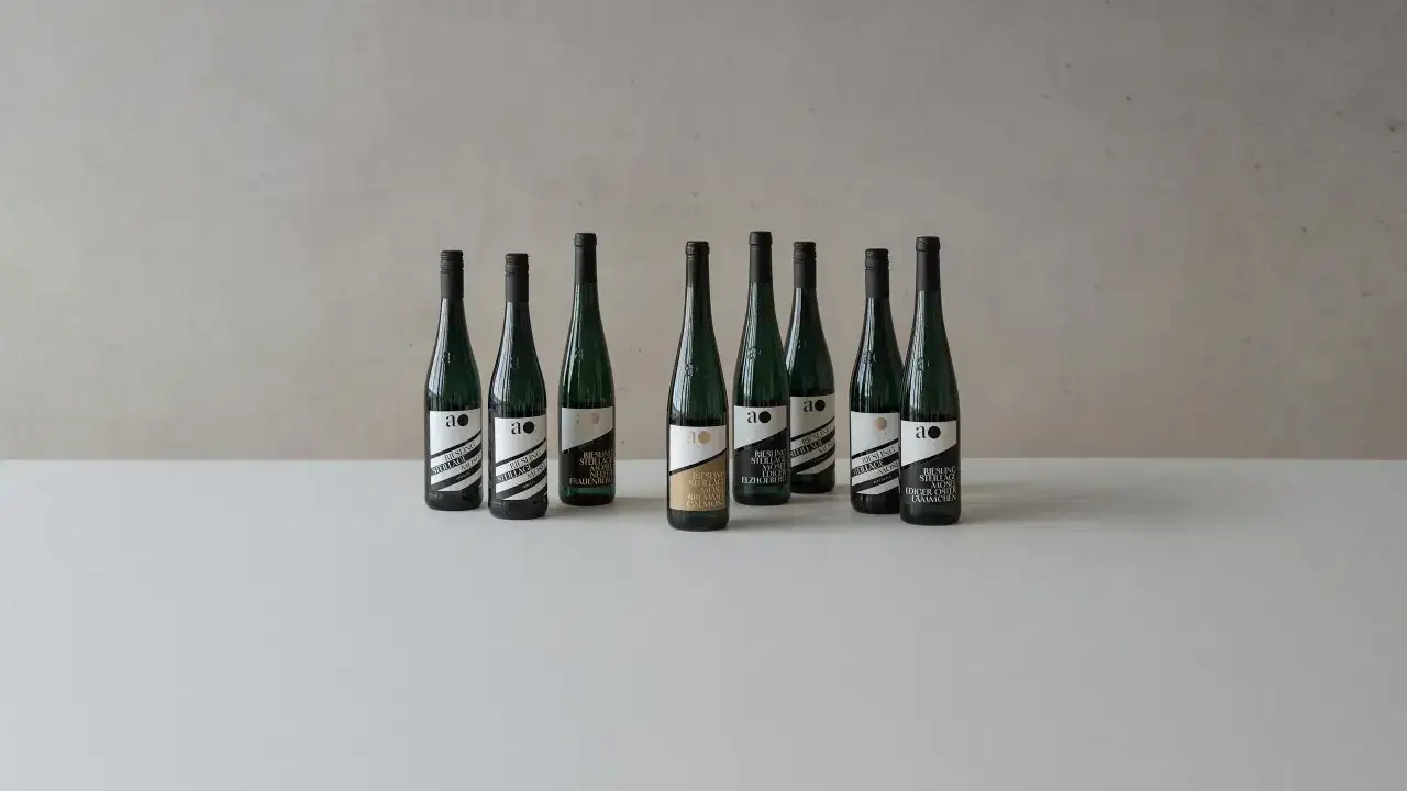 Neun Flaschen Wein der andreas oster weinkellerei stehen auf einem Tisch.
