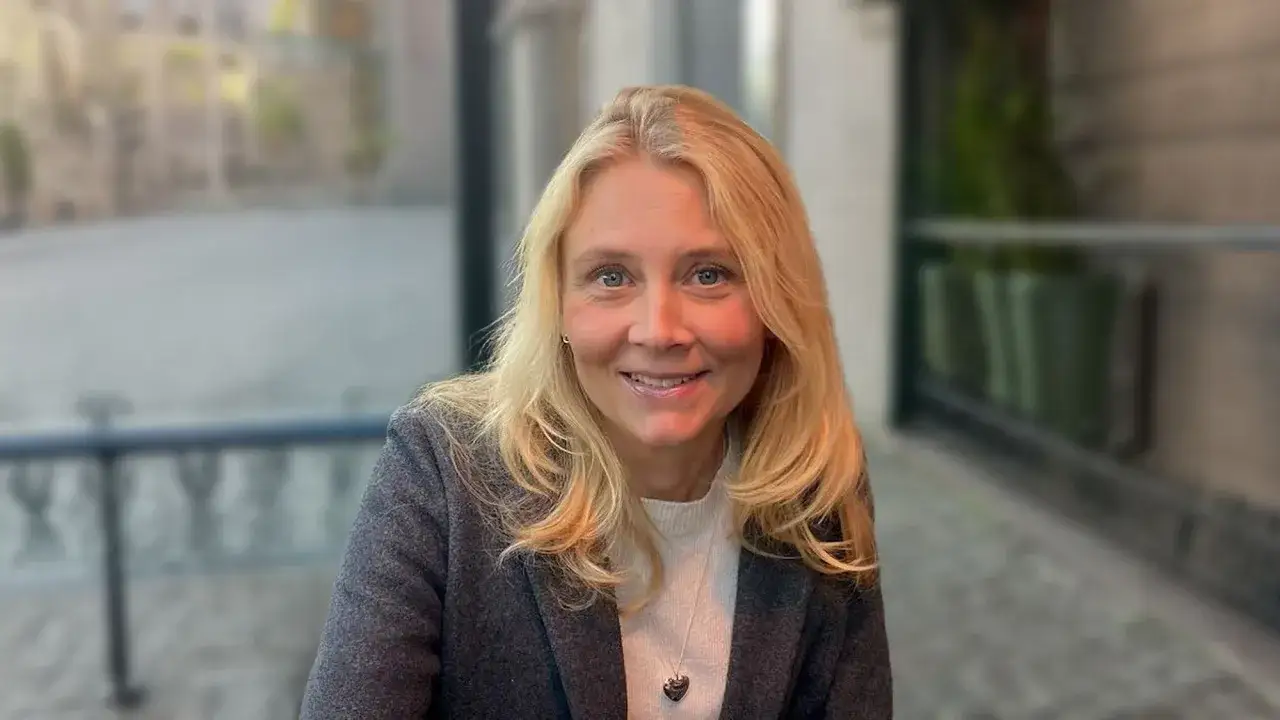 Portr&auml;tt av Lottie Knutsson med blont h&aring;r och bl&aring; &ouml;gon, kl&auml;dd i gr&aring; kavaj.