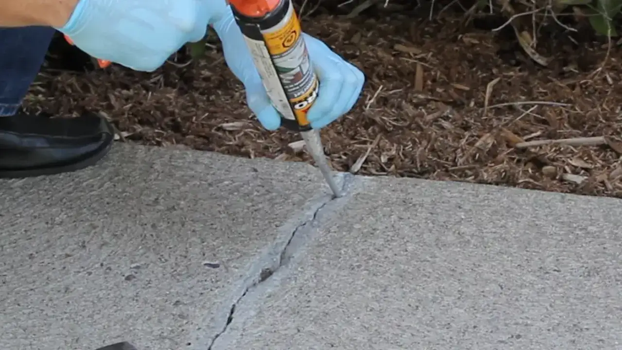 Application d'un produit de r&eacute;paration dans une fissure de dalle en b&eacute;ton.