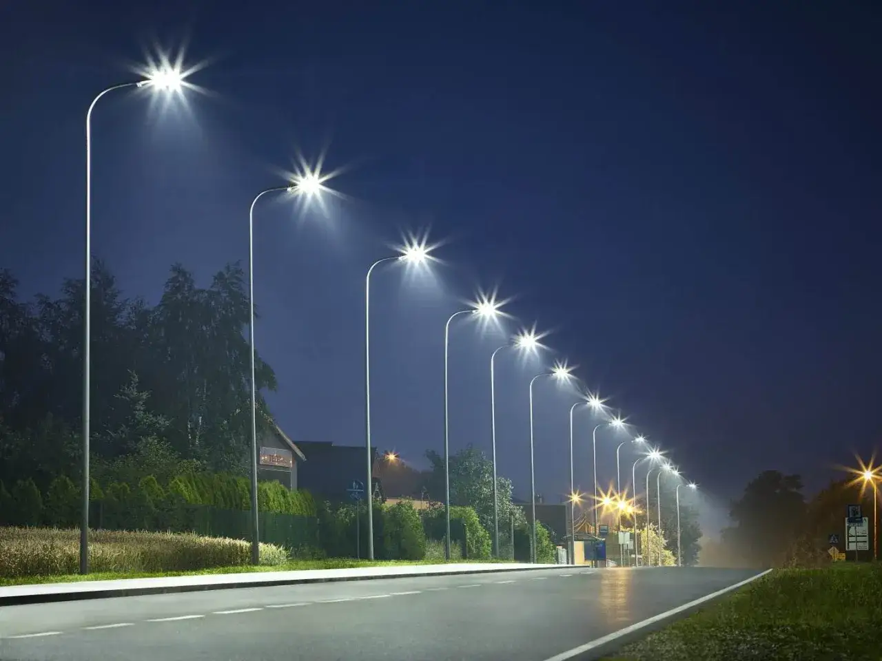 Rząd nowoczesnych lamp miejskich oświetla pustą drogę nocą, tworząc świetlistą aleję.