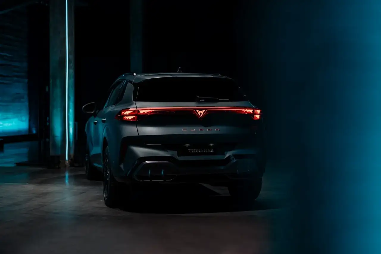 Tylna część Cupra Terramar w ciemnym otoczeniu. Wymiary tego SUV-a podkreślają jego dynamiczną sylwetkę.