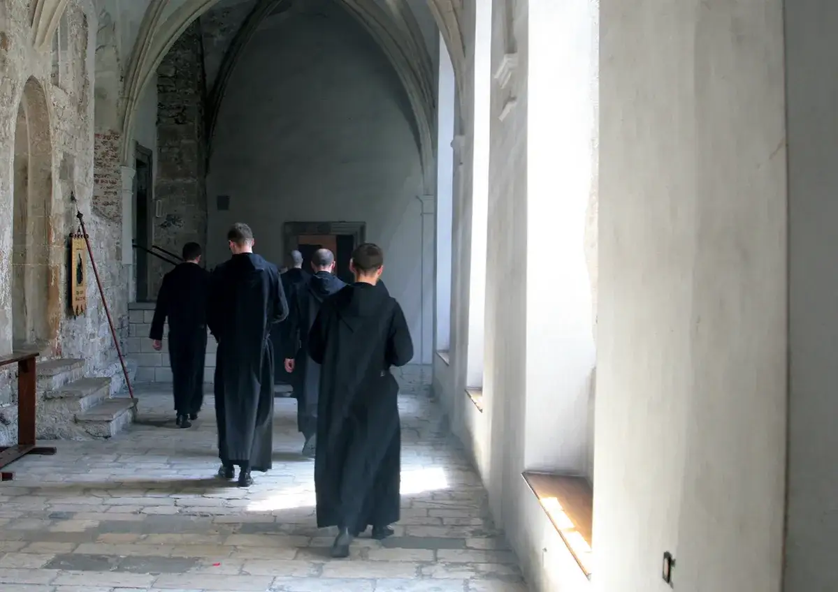 Mnisi w czarnych habitach idą korytarzem klasztornym. Ich życie to ora et labora – modlitwa i praca.
