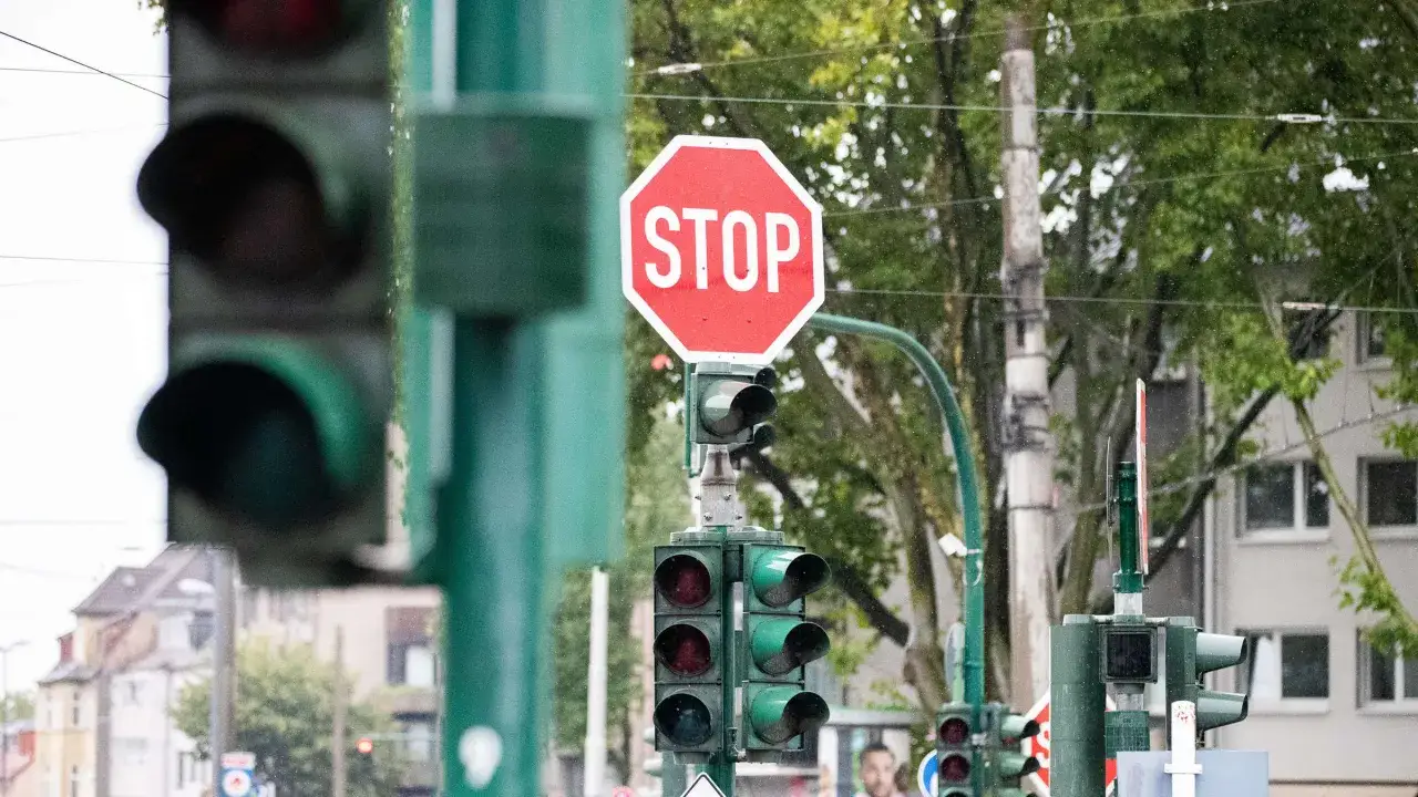 Rote Ampeln und ein STOP-Schild an einer Kreuzung. Der Verkehr wartet, vielleicht auf die 132 bkat.