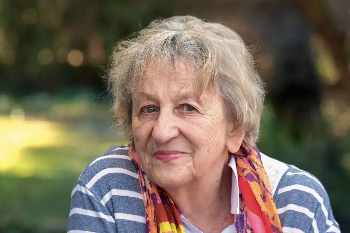 Porträt einer älteren Frau mit grauem Haar und einem bunten Schal, die an ihre Ingrid Noll Kinder denkt.