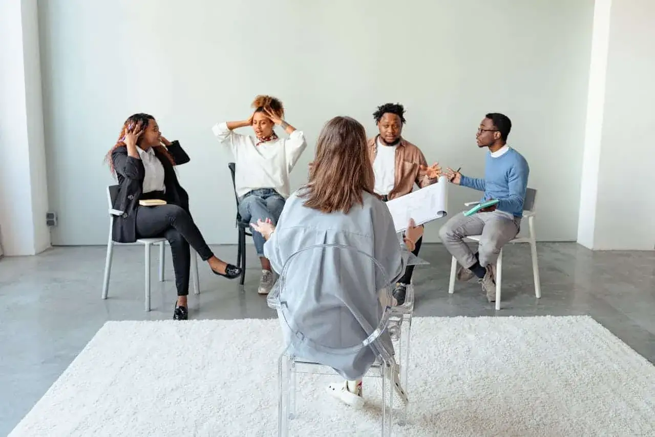 Grupa os&oacute;b uczestniczy w sesji psychoterapii grupowej yalom. Widać emocje i zaangażowanie.