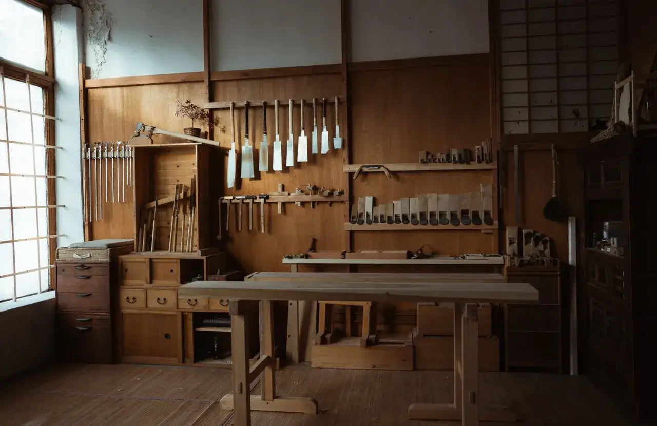 Interno di una falegnameria giapponese, con attrezzi appesi alle pareti e un banco da lavoro in legno.