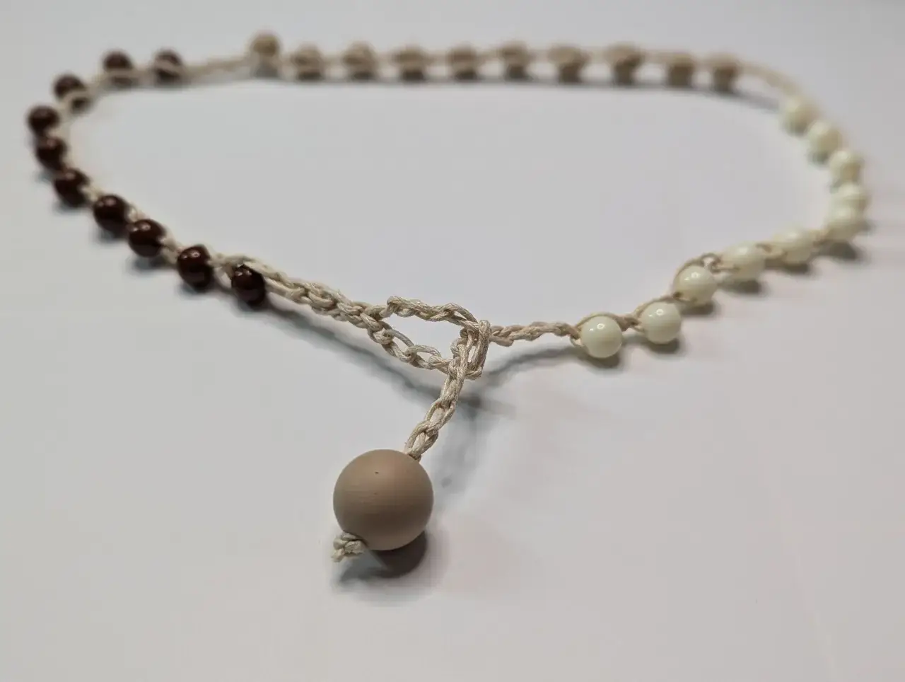 Collares de ganchillo y abalorios de tonos tierra y marfil, con un colgante de bola grande.