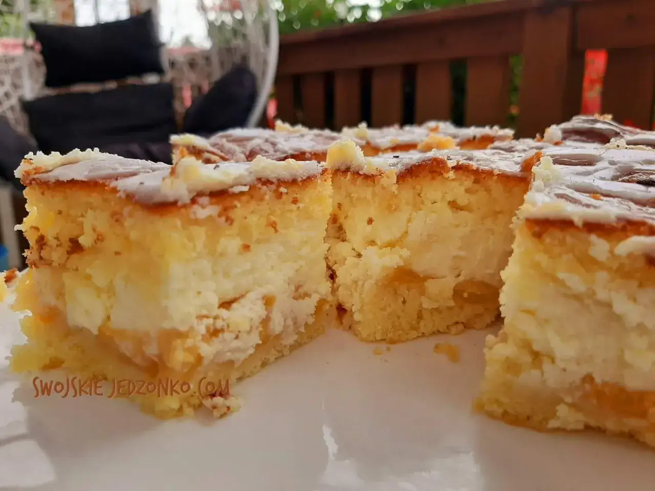 Puszyste ciasto z brzoskwiniami i kremem, pokrojone na kawałki, czeka na spróbowanie.