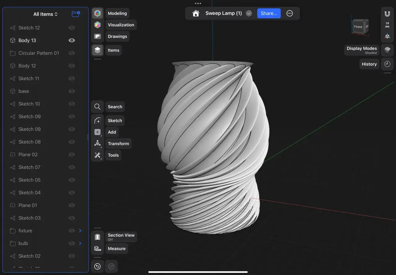 Projektant, **inventor**, tworzy w aplikacji 3D lampę o skręconym kształcie, widoczną na ekranie tabletu.