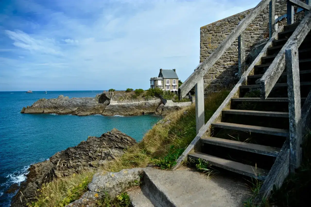 Escalier en bois menant à une maison sur la côte bretonne, avec vue sur la mer près de Cancale Saint-Malo.