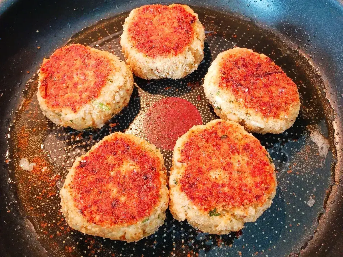 Fünf goldbraune, vegetarische Frikadellen braten in einer Pfanne. Sie duften herrlich nach Gewürzen und sind bereit zum Genießen.