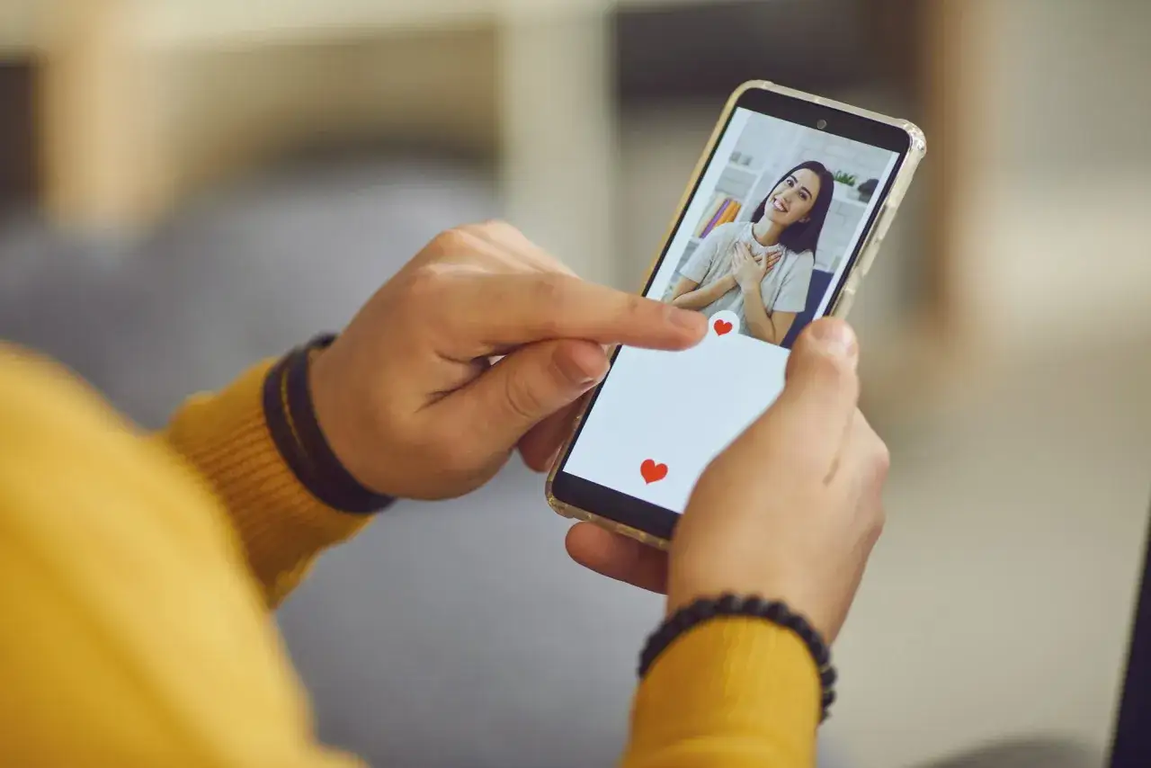 Palec wskazujący przesuwa ekran telefonu, pokazując profil kobiety. To może być początek poszukiwań, jak znaleźć kogoś na Tinderze.
