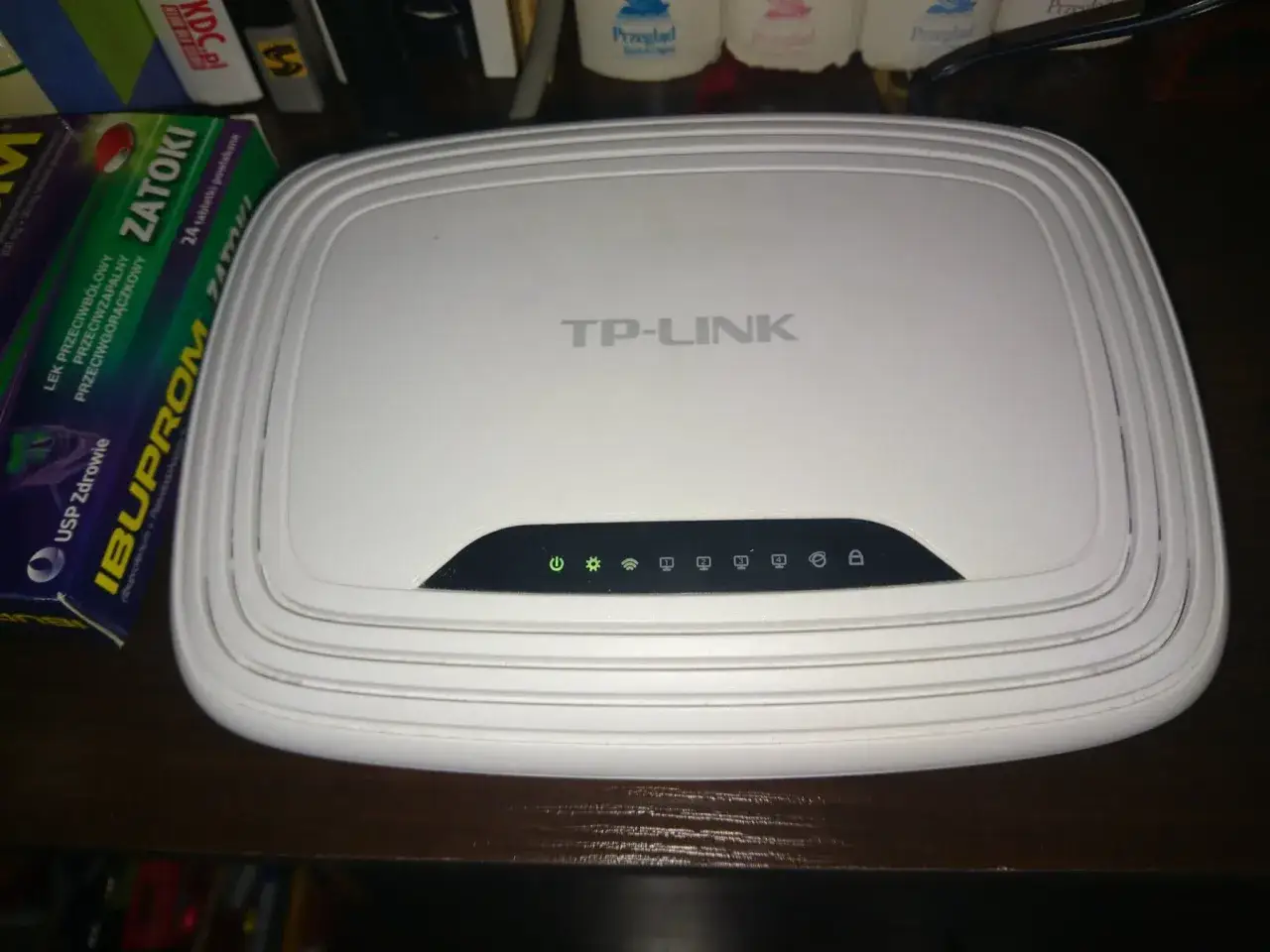 Router TP-Link z zielonymi diodami, sygnalizującymi brak internetu. Obok leki na zatoki.