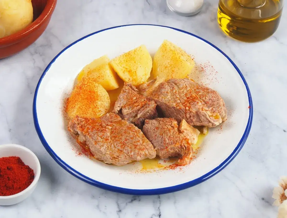 Sabroso plato de carne o caldeiro con patatas cocidas, espolvoreado con pimentón y un chorrito de aceite de oliva.
