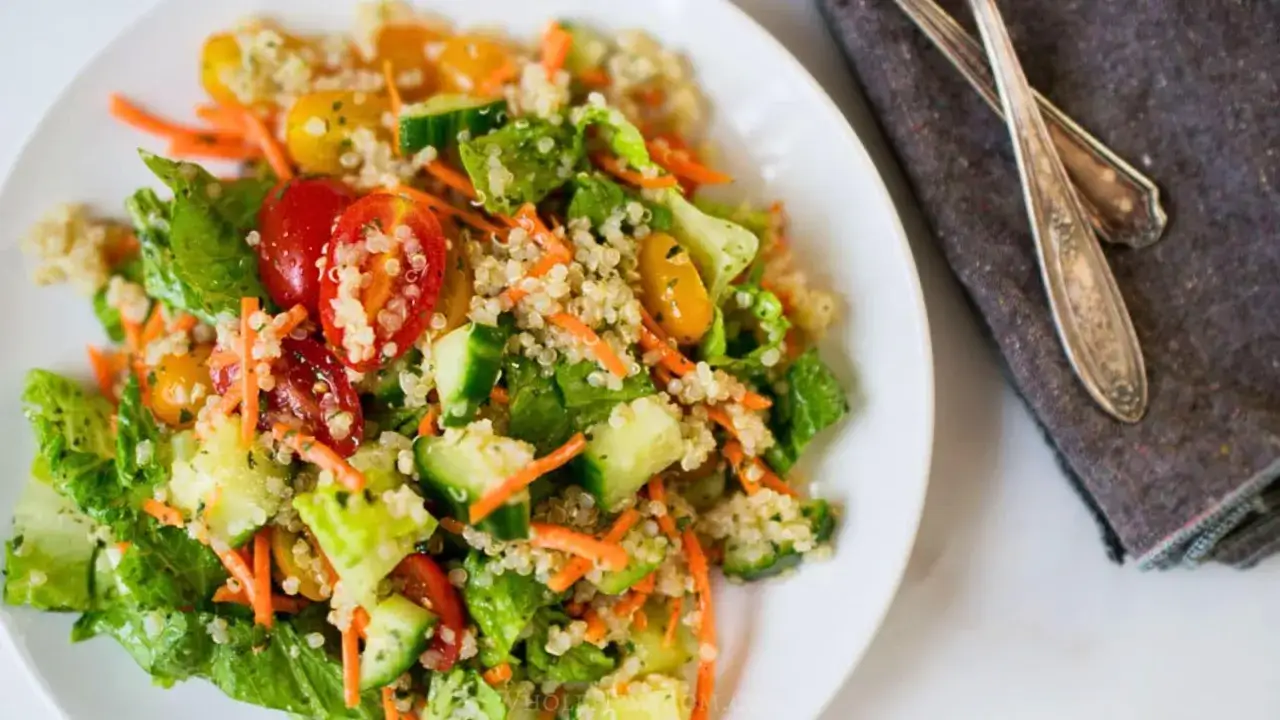 Salade quinoa colorée avec tomates cerises, concombre et carottes râpées. Une assiette fraîche et saine.