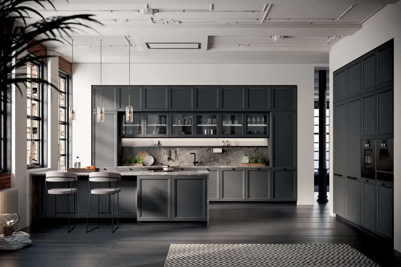 Elegante cucina grigia con isola centrale, bancone con sgabelli e pensili a parete. Il colore delle pareti si armonizza con le tonalit&agrave; scure dell'arredo.