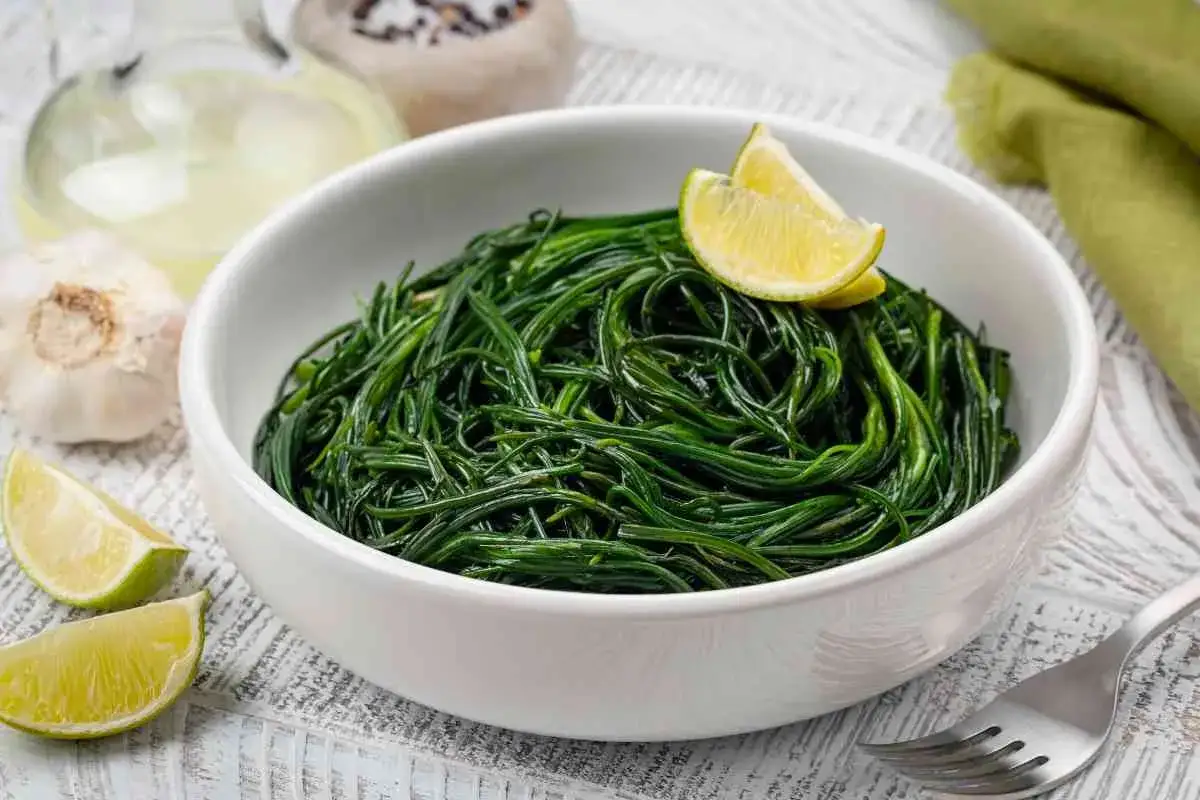 Agretti in padella, un contorno fresco e saporito, guarnito con spicchi di lime.