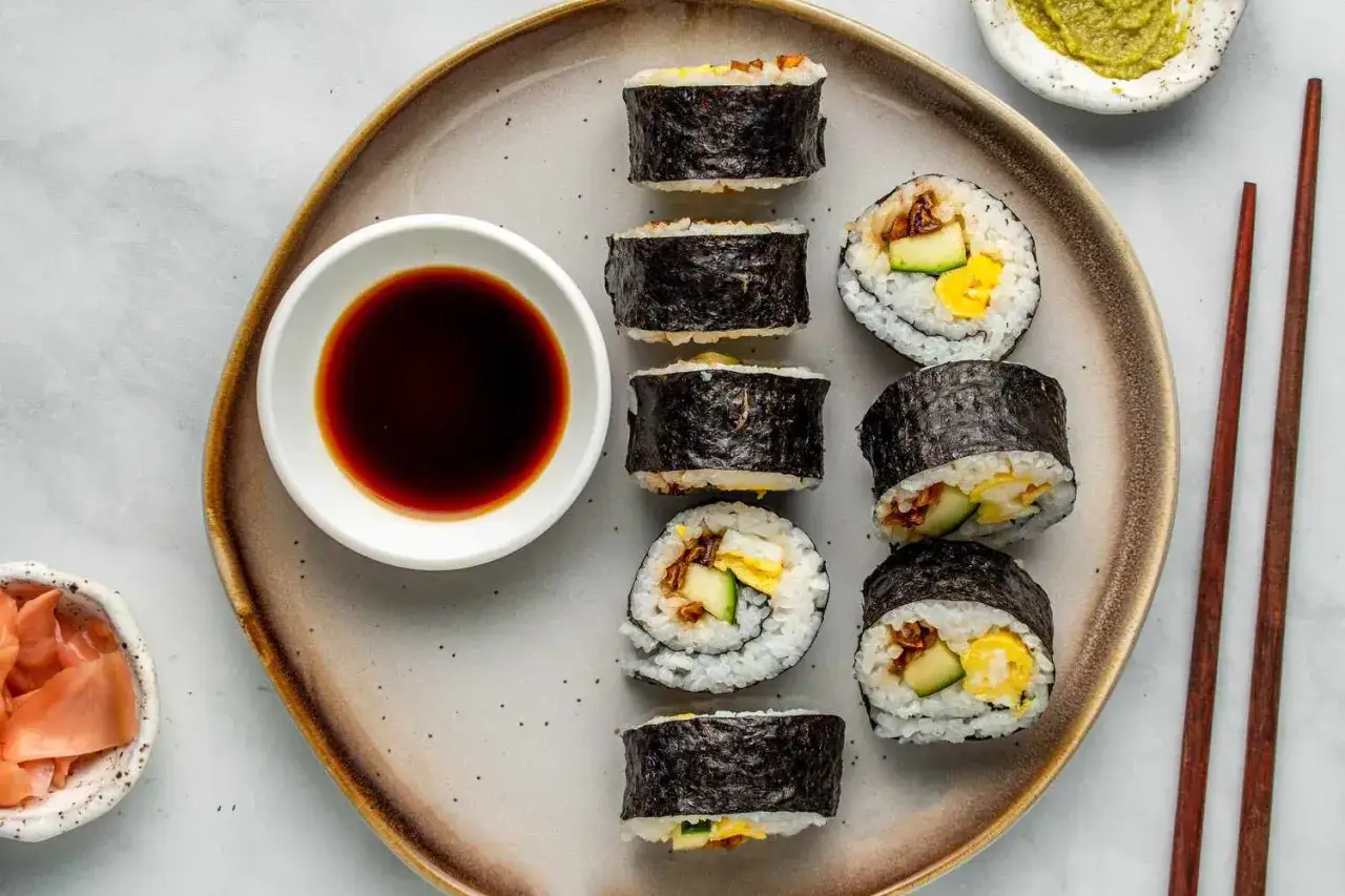 Kilka kawałków futomaków z ogórkiem i jajkiem, podane z sosem sojowym i wasabi.