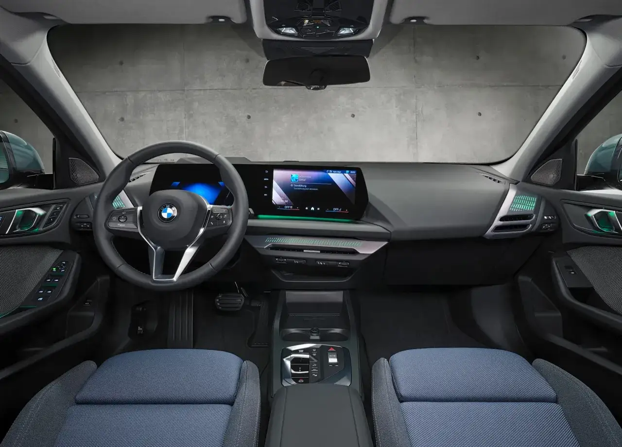 Wnętrze BMW F40 z niebieskimi siedzeniami i nowoczesnym panelem multimedialnym.